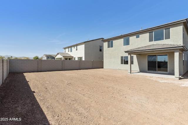 rear view of house featuring a fenced backyard, a patio, and stucco siding