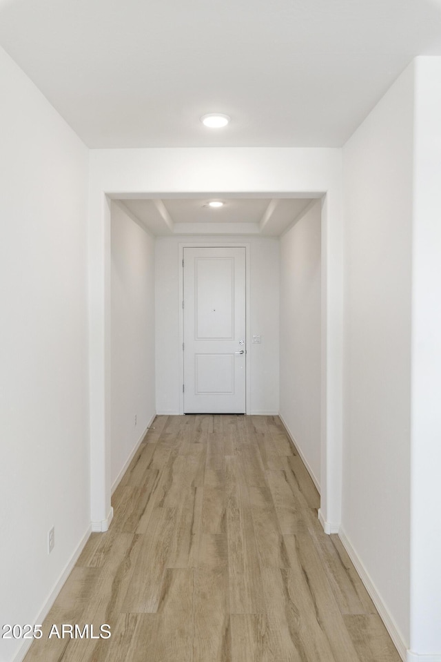 hallway featuring light wood finished floors and baseboards