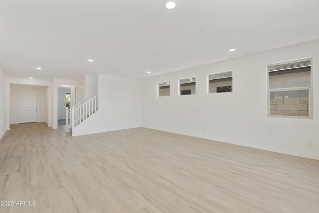spare room with recessed lighting, light wood-style flooring, and stairs