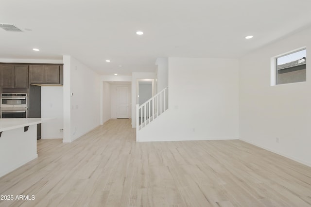unfurnished living room featuring light wood-type flooring, visible vents, recessed lighting, and stairs