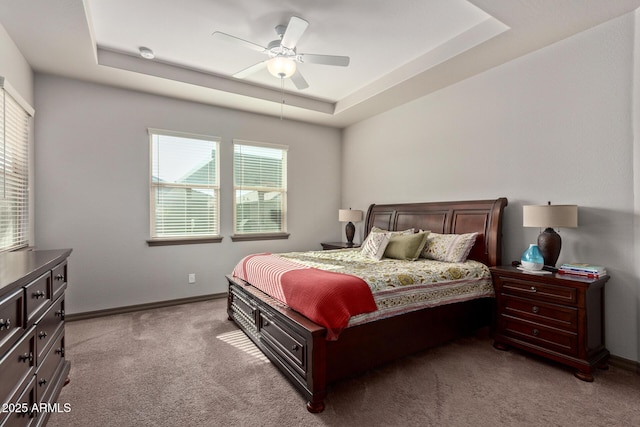 bedroom with ceiling fan, a tray ceiling, and light carpet