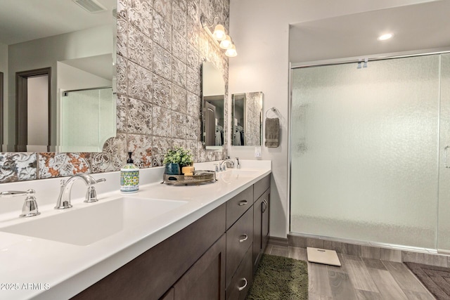 bathroom featuring a shower with shower door and vanity