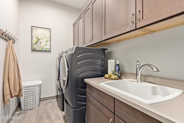 laundry room with cabinets, sink, separate washer and dryer, and light hardwood / wood-style floors