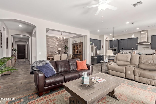 living room with ceiling fan with notable chandelier and dark wood-type flooring