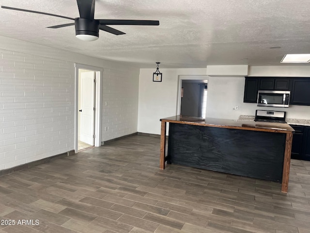 kitchen with brick wall, appliances with stainless steel finishes, and a textured ceiling