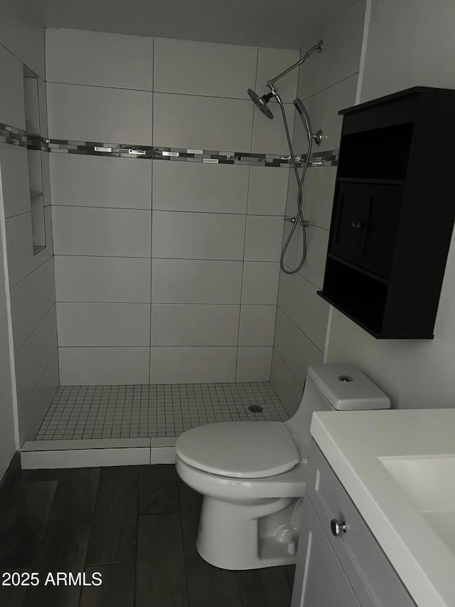 bathroom featuring vanity, toilet, tile patterned flooring, and a tile shower