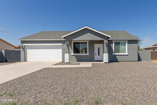 view of front facade with a garage, driveway, fence, and stucco siding