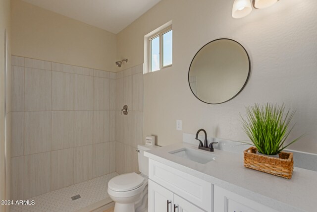 bathroom with vanity, toilet, and a tile shower