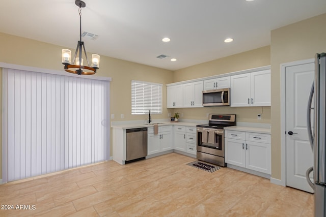 kitchen featuring stainless steel appliances, decorative light fixtures, and white cabinets