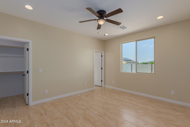 unfurnished bedroom with a spacious closet and ceiling fan