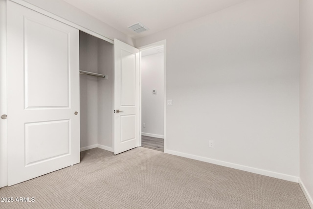 unfurnished bedroom featuring light colored carpet and a closet