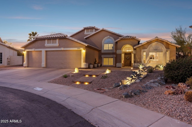 mediterranean / spanish-style house featuring a garage, concrete driveway, a tile roof, and stucco siding