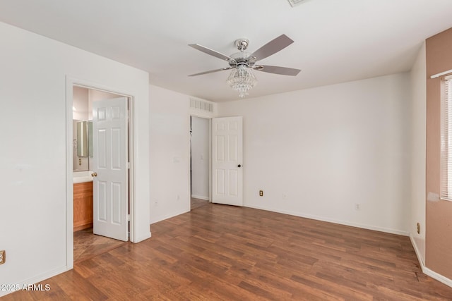 12425 W Willow Ave, El Mirage, AZ 85335 - unfurnished bedroom featuring wood finished floors, baseboards, connected bathroom, and a ceiling fan