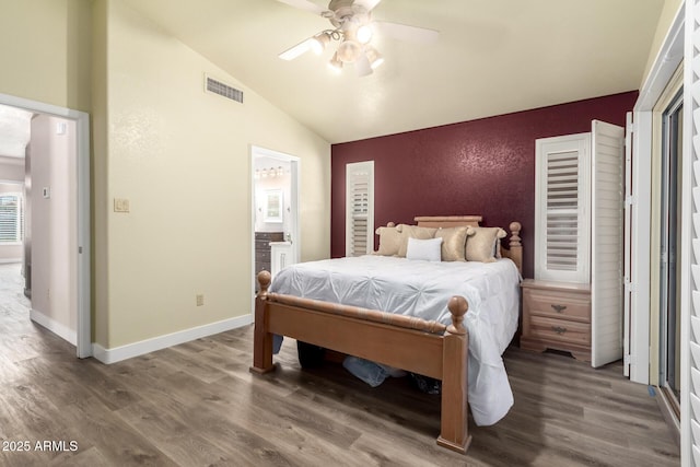 bedroom featuring vaulted ceiling, ensuite bath, wood finished floors, and visible vents