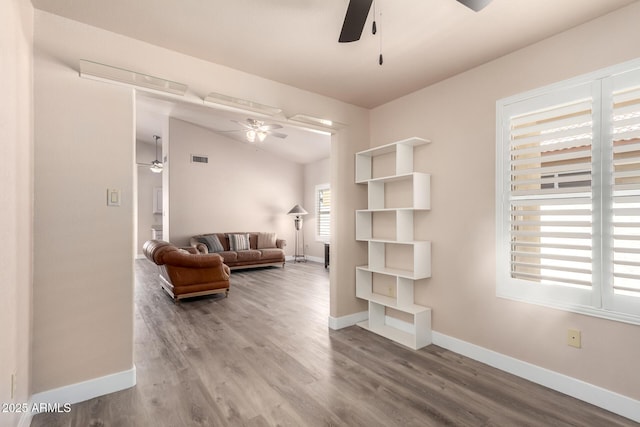 living room with a ceiling fan, visible vents, wood finished floors, baseboards, and lofted ceiling