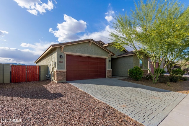 18360 W Alice Ave, Waddell, AZ 85355 - ranch-style house with stucco siding, an attached garage, stone siding, decorative driveway, and a gate