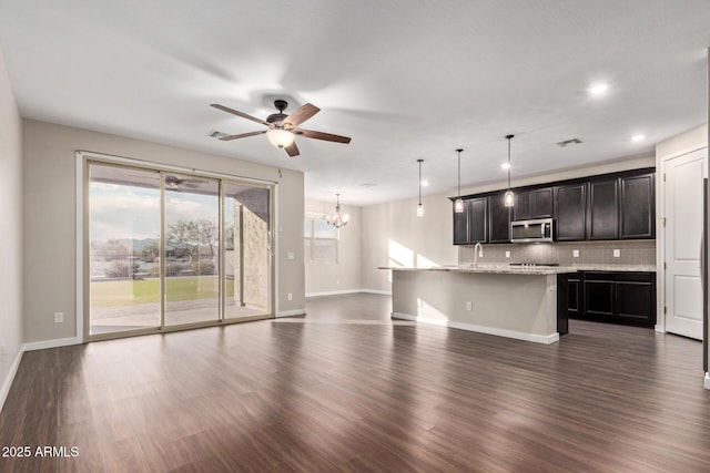 18360 W Alice Ave, Waddell, AZ 85355 - unfurnished living room with dark wood-style flooring, visible vents, baseboards, a sink, and ceiling fan with notable chandelier