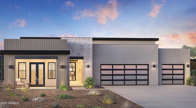 contemporary home featuring french doors, a garage, driveway, and stone siding