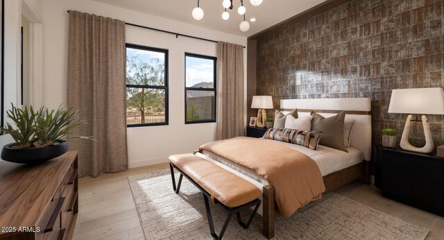 bedroom featuring baseboards, wood finished floors, an accent wall, and a chandelier