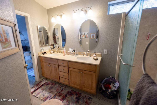 bathroom featuring double vanity, tile patterned floors, a textured wall, and a shower with door
