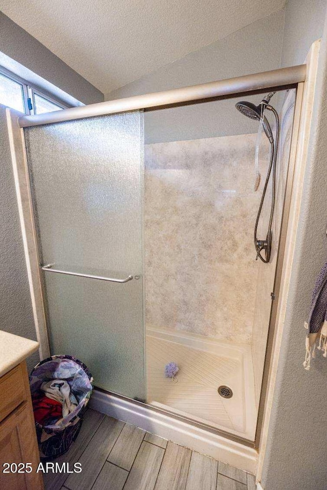 bathroom featuring wood finished floors, a stall shower, and vanity