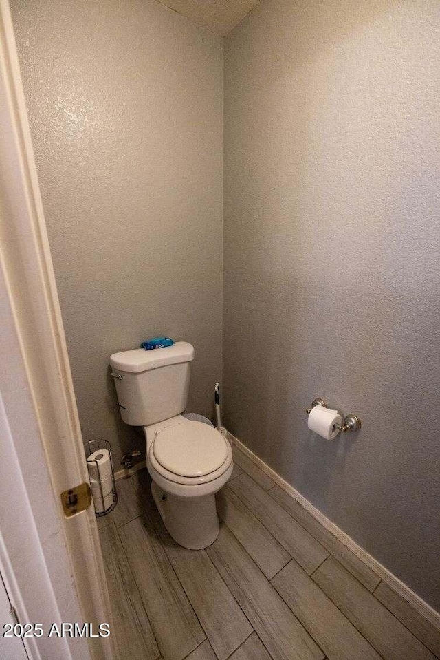 bathroom featuring toilet, wood finished floors, and baseboards