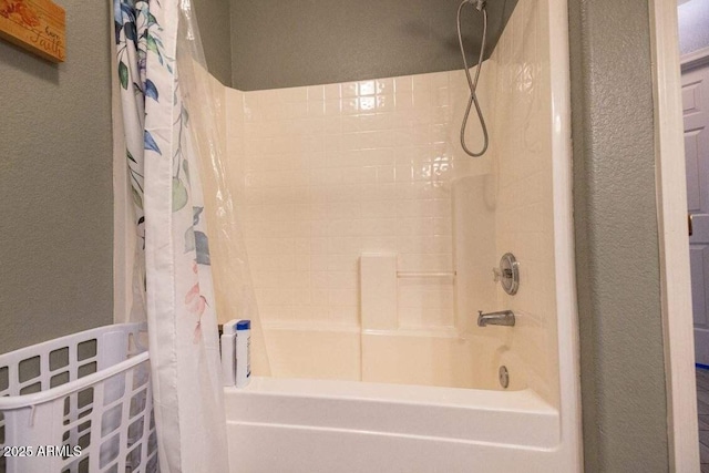 full bathroom featuring shower / tub combo with curtain and a textured wall