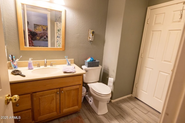bathroom featuring wood finished floors, vanity, toilet, and baseboards