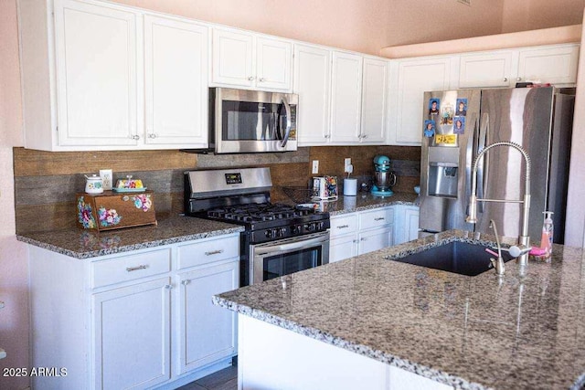 kitchen featuring stainless steel appliances, light stone counters, white cabinetry, tasteful backsplash, and a sink