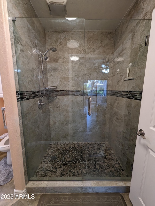 bathroom with tile patterned floors, toilet, and walk in shower