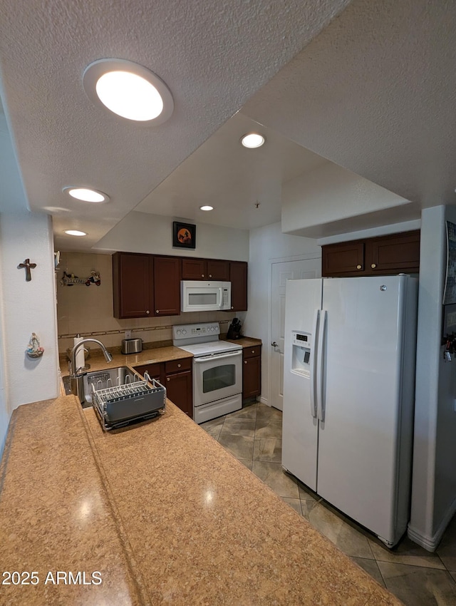 kitchen featuring white appliances, a textured ceiling, sink, light tile patterned flooring, and dark brown cabinets