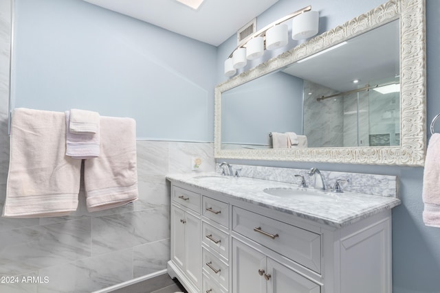 bathroom with tile walls, an enclosed shower, and vanity