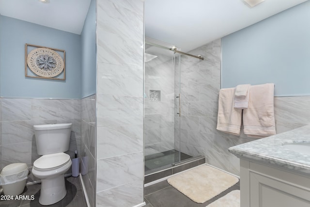 bathroom featuring tile walls, vanity, toilet, and a shower with shower door