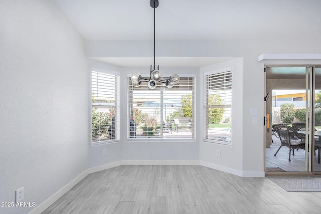 unfurnished dining area featuring a chandelier, a wealth of natural light, and baseboards