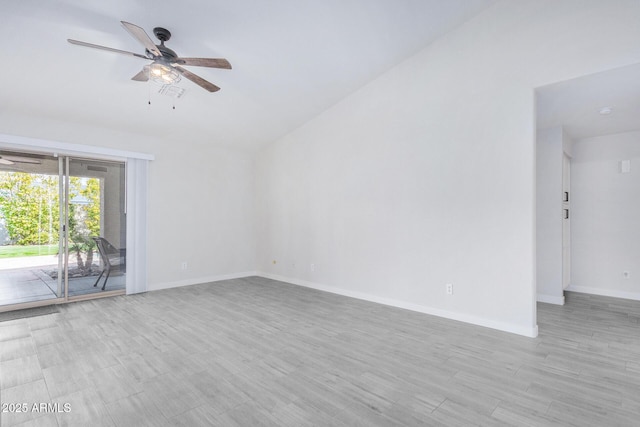 spare room featuring a ceiling fan, lofted ceiling, light wood-type flooring, and baseboards