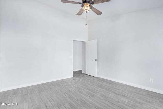 spare room featuring ceiling fan, light wood-style flooring, and baseboards