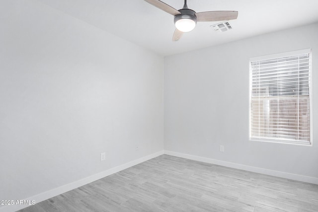 empty room with light wood finished floors, baseboards, visible vents, and a ceiling fan