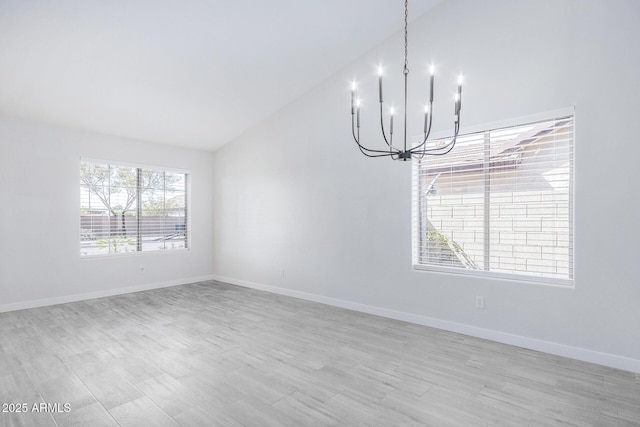 spare room featuring lofted ceiling, light wood-type flooring, baseboards, and a notable chandelier