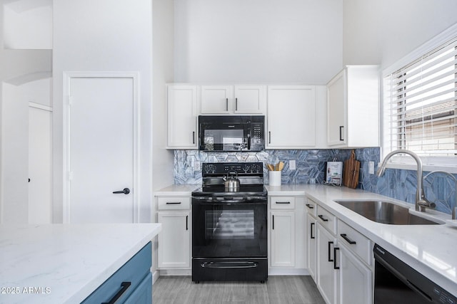 kitchen featuring tasteful backsplash, white cabinets, a sink, light stone countertops, and black appliances