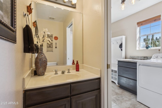 bathroom with toilet, visible vents, vanity, tile patterned floors, and washer / dryer