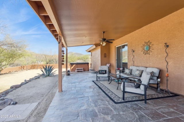 view of patio / terrace featuring a hot tub, an outdoor hangout area, a mountain view, ceiling fan, and a fenced backyard