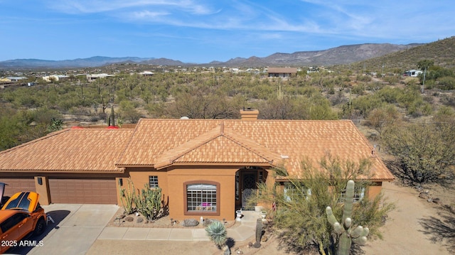 view of front of home with driveway, a tile roof, a mountain view, and stucco siding