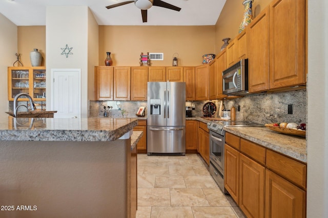 kitchen with appliances with stainless steel finishes, brown cabinets, visible vents, and decorative backsplash