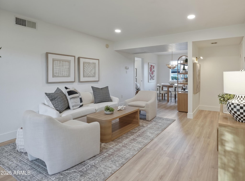 living room featuring a notable chandelier and light wood-type flooring