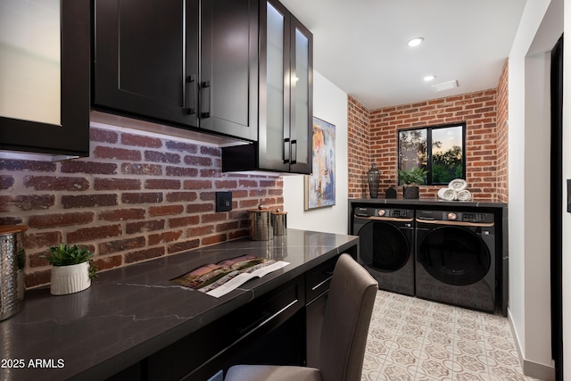 8708 E Rancho Vista Dr, Scottsdale, AZ 85251 - kitchen featuring washer and dryer, dark cabinets, brick wall, and dark stone counters
