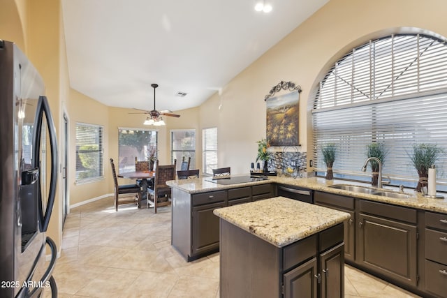 kitchen featuring sink, a center island, appliances with stainless steel finishes, plenty of natural light, and light stone countertops