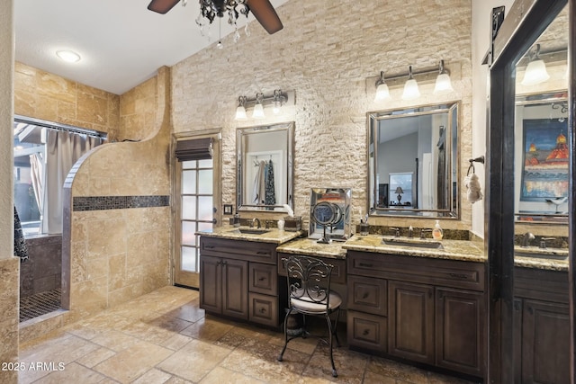 bathroom with a tile shower, vanity, and ceiling fan