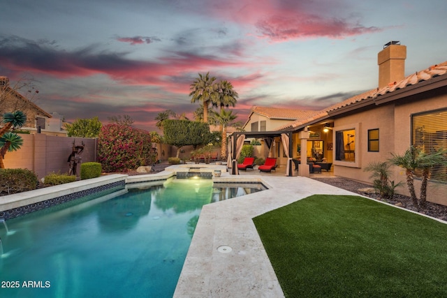 pool at dusk featuring outdoor lounge area, a lawn, and a patio area