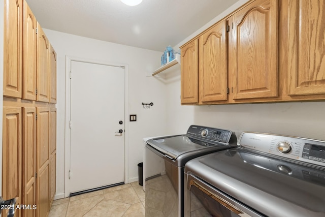 washroom featuring light tile patterned floors, washing machine and dryer, and cabinets