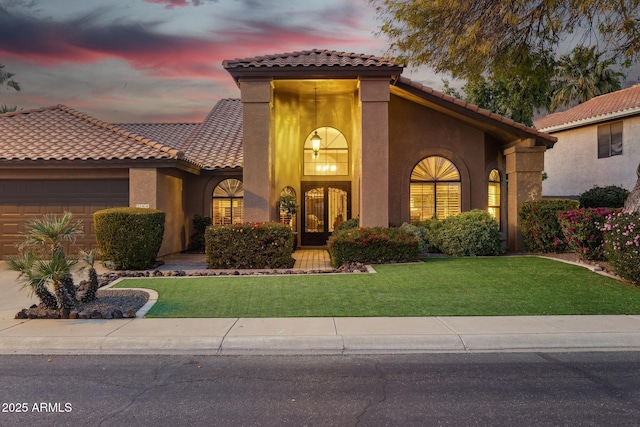 mediterranean / spanish-style home with a garage and a lawn